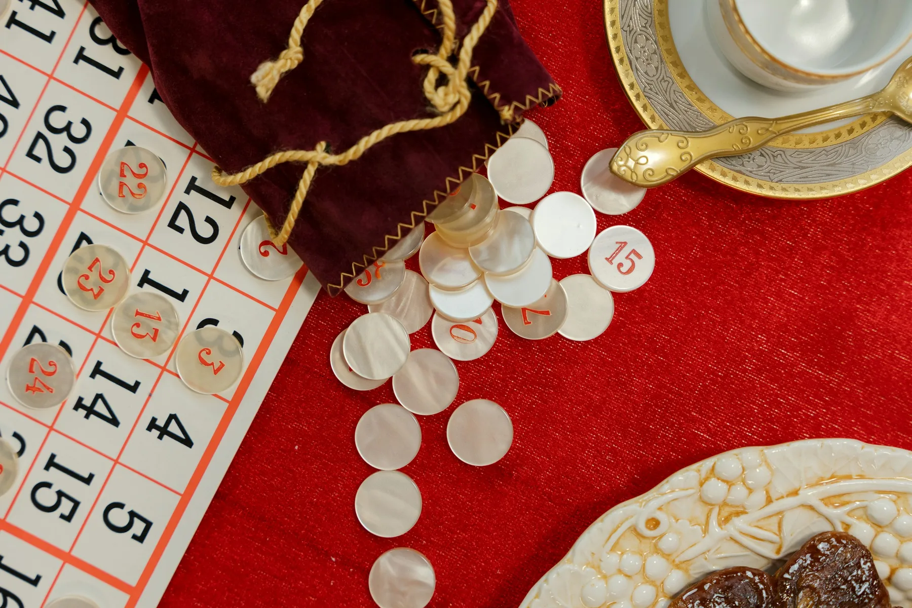 Cartella della tombola con i numeri e un sacchetto di velluto da cui escono i gettoni